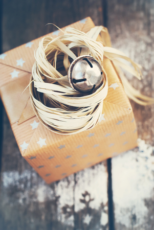 Christmas Gift with Jingle Hand Bell and Natural Twine on Wooden Background. Toned imageの写真素材