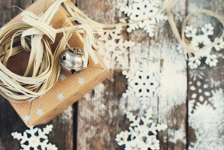 Jingle Hand Bell and Natural Twine as Decor on Christmas Box. Wooden Background with Snowflakes....
