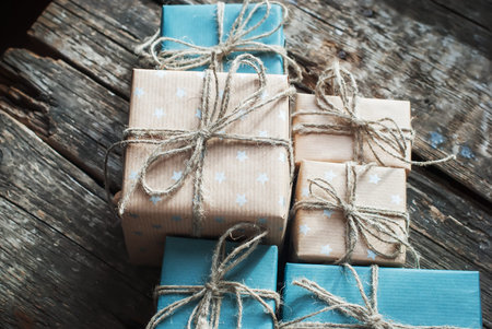 Festive Boxes are Packed into a Brown Paper with Linen Cord on Wooden Background