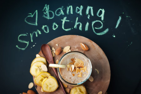 Fruit banana smoothies with milk, almond, flakes, slices of banana with letters on a black chalkboardの写真素材