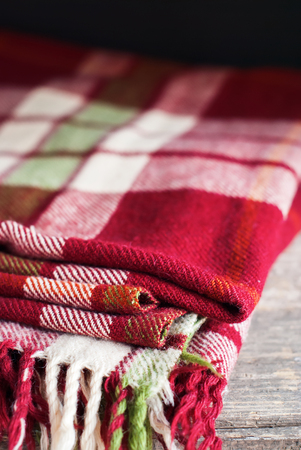 Red Vintage Blanket Tartan Cozy Plaid Lie on Wooden Table on Dark Background Copy Space Interiorの写真素材