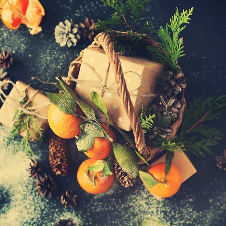 Christmas New Year Composition with Tangerines Boxes Pine cones Greens in Basket Black Background Holiday Decoration to Russian Tradition Tonedの写真素材