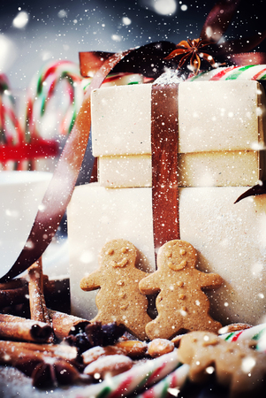 Gingerbread Men near with Boxes on Christmas Table. Toned in Pastel Color. Drawn Falling Snowの写真素材