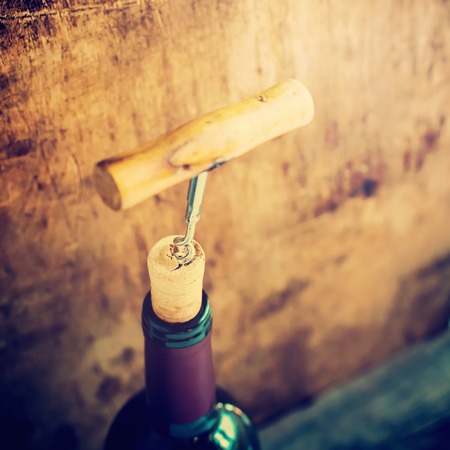 Bottle Wine with Corkscrew on Wooden Background Opening Process Tonedの写真素材