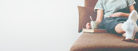 Photo Woman Sofa Bed with Cup Milk Rest Plaid Soft Toned Lifestyle Long Banner Copy Spaceの写真素材