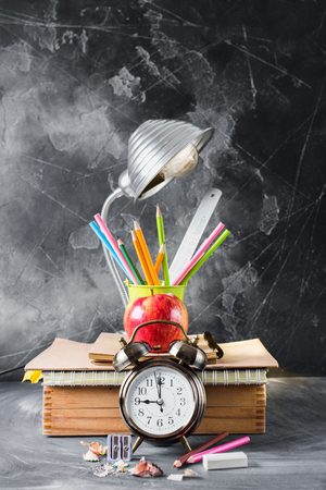 Group of Objects Close up Concept Back To School Alarm Clock Color Chalk Pencil Apple Notebook Lamp Stationery Black Blackboard Background Behind. Design Copy Space Education Supplies Verticalの写真素材