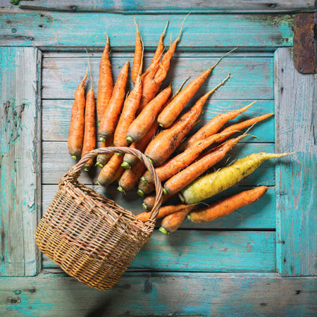 Natural Organic Carrots in Basket Lies Wooden Blue Background Rustic Style Top Viewの写真素材