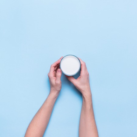 Female Hands Holds One Object Fresh Glass Milk Color Blue Background Top View Flat Layの写真素材