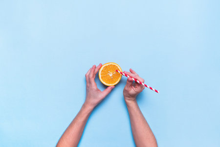 Female Hands Holds Straw Fresh Juice Fruit Squeeze Orange Color Blue Background Top View Flat Layの写真素材