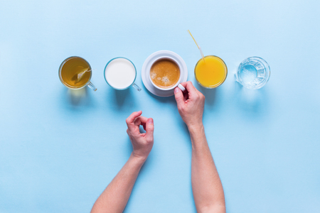 Female Hands Holds Group Useful Colorful Beverages Drink Coffee Milk Tea Orange Juice Water Flat Lay Still Life Table Top View Blue Backgroundの写真素材