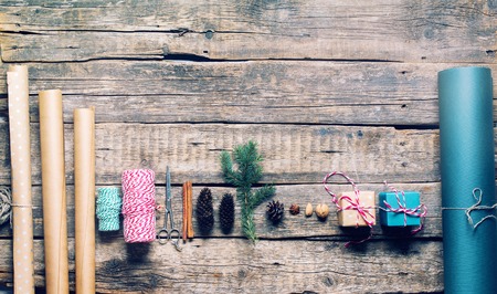 Packing Christmas Gifts in Vintage Beige Blue Roll Paper and Natural Decor Fir Branches Cones Cinnamon on Wooden Retro Desk. Top View Flat Layの写真素材