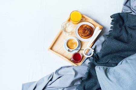 Breakfast Bed Wooden Tray Coffee Bun Grey Linens Bedding Sheet Pillow Coverlet Hotel Room Early Morning at Hotel Background Concept Interior Copy Spaceの写真素材