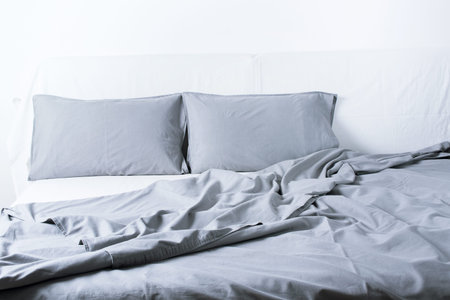 Close Up Grey Linens Bedding Sheet Pillow Coverlet White Wall Room Background Messy Bed Concept...