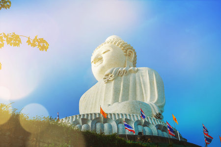 statue stone giant Big Buddha with thai flags high hilltop Phuket Thailand sky background morning...