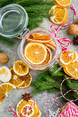 Homemade dried slices of oranges in the jar with fir and nuts.の写真素材