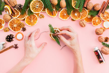 Female hands decorated tie up with cord homemade slices dried oranges as Christmas natural and organic gift.の写真素材