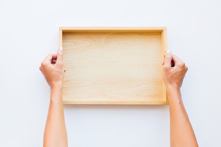 Female hands holding wooden empty tray. Woman in in apron white black apron. Top viewの写真素材