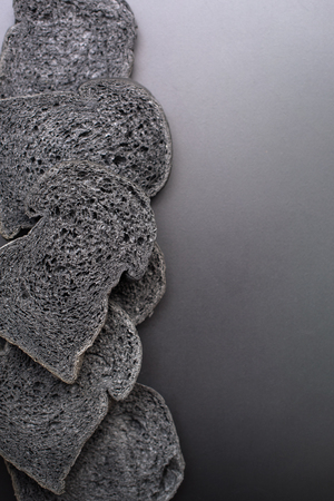 Organic sliced homemade charcoal bread on black background. Clean good food. Vertical photo copy spaceの写真素材