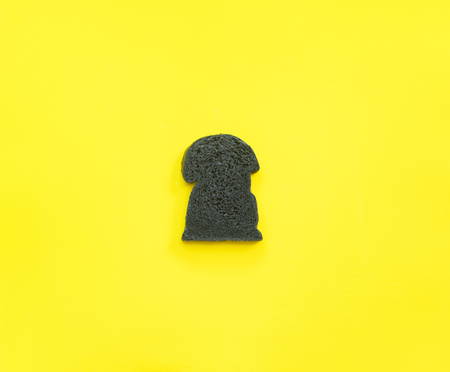 One slice homemade charcoal bread on yellow background. Copy space. Clean good foodの写真素材