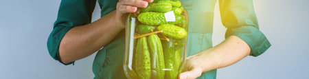 Woman hands holding jar of salty preservation pickles cucumber. Organic farm vegetables food. Banner...
