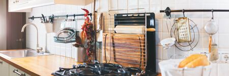 Panoram of kitchen accessories chopping board, tray, supports, spoons, plate on wooden table top. Rustic country dishes table ware fresh grocery different stuff white tile background. Bannerの写真素材