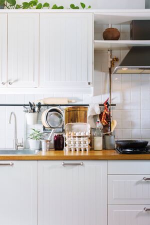 Kitchen decorative details dried pepper, vintage spoons, chopping board, tray, plate on wooden table top. Rustic country dishes table ware, fresh grocery different stuff white tile backgroundの写真素材