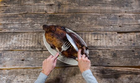 Woman hands cutting Christmas or Thanksgiving turkey roasted whole duck on rustic vintage wooden table. Preparation to celebration traditional dinner. Top viewの写真素材