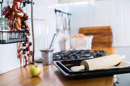Kitchen accessories rolling pin, tray on rustic country wooden table top. White interior kitchen facades dishes table ware different stuff. White tile backgroundの写真素材