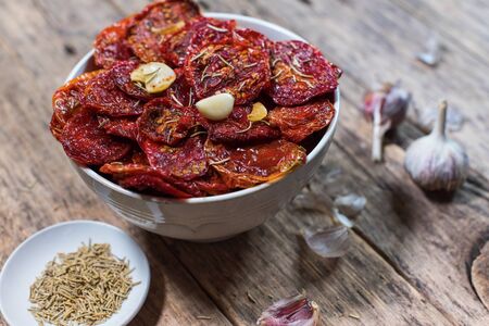 Dried tomatoes with garlic in bowl on dark wooden tableの写真素材