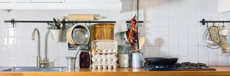 Kitchen details dried pepper, vintage spoons, chopping board, tray, plate on wooden table top. Rustic country dishes table ware, fresh grocery different stuff white tile background. Long bannerの写真素材