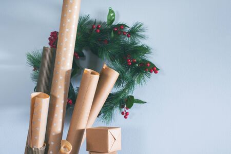 Vintage wrapping beige craft paper decor. Wreath holly berry on gray wall background. Concept of preparation to New Year and Christmas holidaysの写真素材