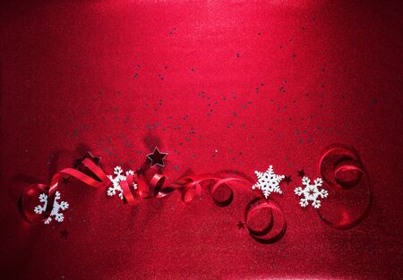 Bright New Year ribbon and snowflakes on red colour sparkle paper background. Holiday festive concept. Christmas ornate decoration. Copy spaceの写真素材