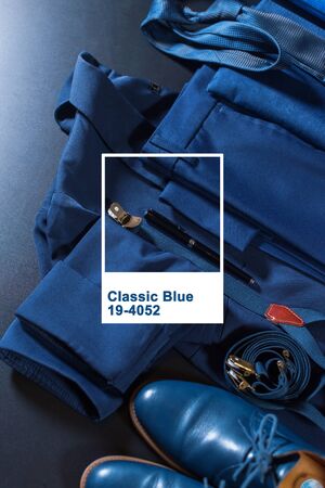 Classic set men clothes blue suit, shoes, belt, watch, notebook, speaker on dark background. Top view. Flat lay. Frame and text above image color of the yearの写真素材