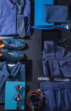 Order in set men classic clothes and accessories. Blue suit skirt, belt. shoes, watch, tablet, notebook. phone, earphones on dark background. Top view. Flat layの写真素材