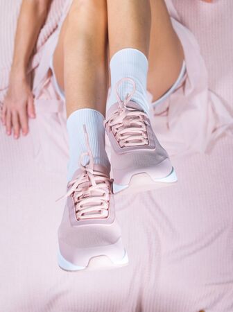 Elegant slim legs of girl in pink sport shoes and in light transparent, cipher skirt lying on knitted plaid.の写真素材