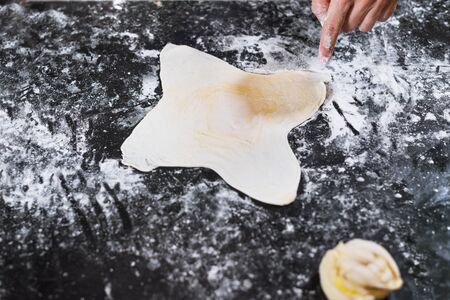 Female hand stuffing rolled puff pastry with minced meat on table at homeの写真素材