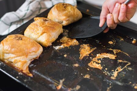 Female hands is taking a freshly baked samsa from the oven tray.の写真素材