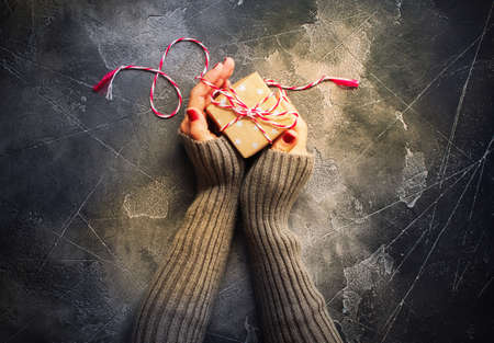 Female Hands Holding Festive Vintage Christmas Beige Box with Twine Cord Single Object on Holiday Snow Background Top View Flat Lay Advent Giftの写真素材