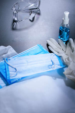 Group of objects. Folding medical protective clothing, masks, glasses and sanitiser on black ready remove to store room. Stop coronavirus. Finished pandemic crisis. End quarantine. Mask off. Top viewの写真素材