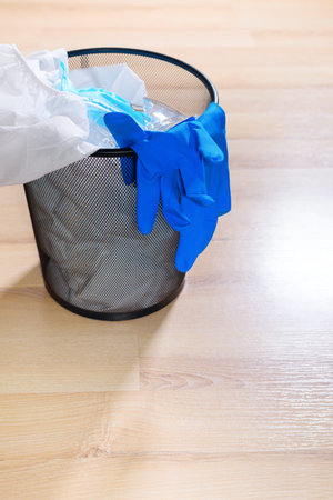 Medical protective clothing, masks, glasses and hand sanitiser are in the rubbish on floor. Stop...