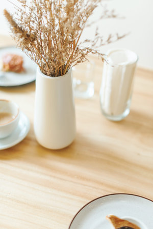 White dishes in militarism style on the table with dried flowers in the vase in cafe