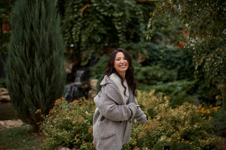 Portrait of pretty asian kazakh brunette woman with charming smile walking along outdoorsの写真素材