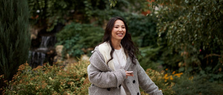 Portrait of pretty asian kazakh brunette woman with charming smile walking along outdoorsの写真素材