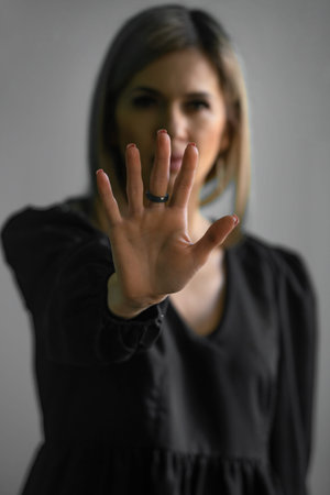 Girl, young woman in dark clothes shows palm, hand forward, stop sign and no. Hand signs, the...
