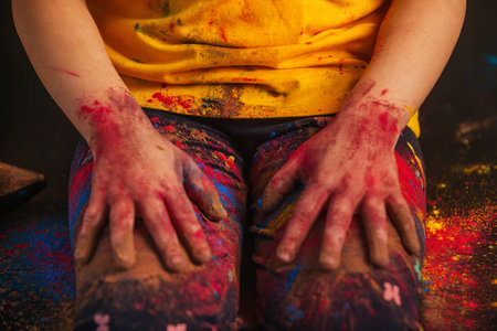 close-up childrens hands in colorful vibrant Holi colors lie on their knees.の写真素材