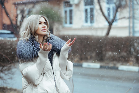 portrait of a beautiful girl in winter during the falling snow on a city streetの写真素材