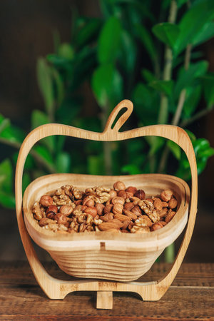 Mix of nuts in a wooden basket on a wooden background almonds, hazelnuts and walnuts in the bright rays of the sun. Natural and healthy nutritionの写真素材