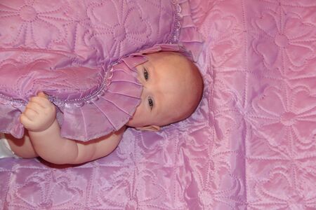 the baby lies on a pink blanket with pink pillowの写真素材