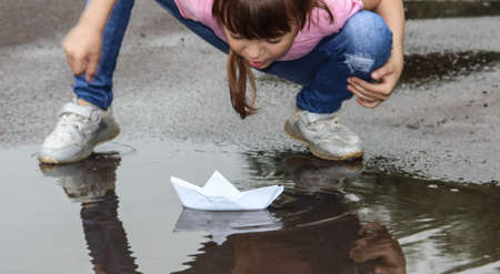 Children play with a puddle of paper boats. Donetsk 07/05/2020 Petrovsky district.のeditorial素材