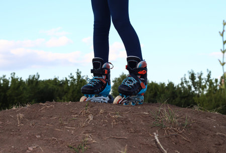 Feet in roller skates on a mountain against the background of nature.